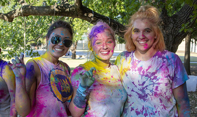 a group of students covered in rainbow colored powder after a fun event