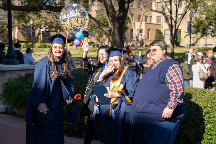 A family taking a photo with a Texas 野狼社区 graduate in full cap and gown